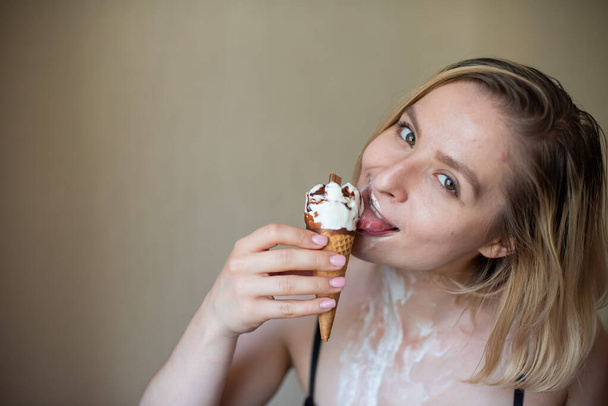 Sexy bionda lecca un cono cialda. Il gelato si sta sciogliendo, drenando eroticamente attraverso il corpo di una donna attraente. Bella ragazza spalmata di gelato. - Foto, immagini