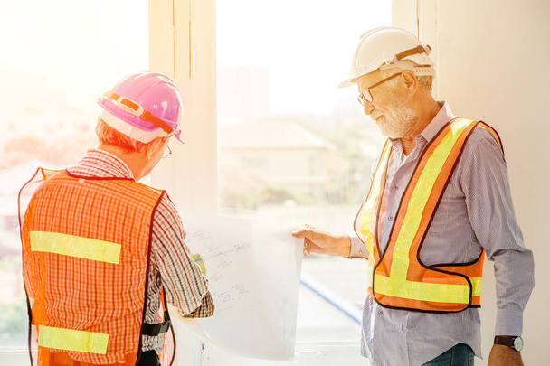 два инженера-строителя, работающие вместе, консультируя по плану этажа здания на строительной площадке
 - Фото, изображение