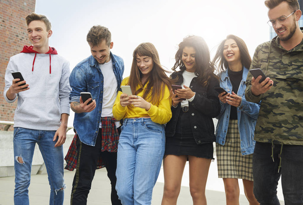 Grupa młodych ludzi patrzących na telefon komórkowy  - Zdjęcie, obraz