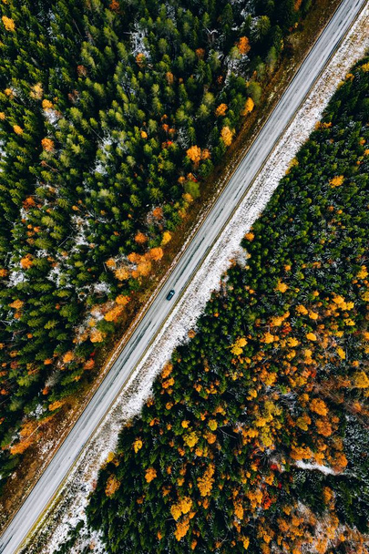 Vista aérea del primer bosque de color otoño de nieve y una carretera con coche en Finlandia
. - Foto, Imagen