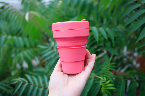 female hand holding pink plastic cup - Φωτογραφία, εικόνα