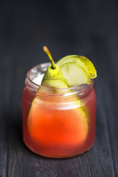 homemade sweet pear in cherry jelly in a glass jar on a dark wooden background - Φωτογραφία, εικόνα