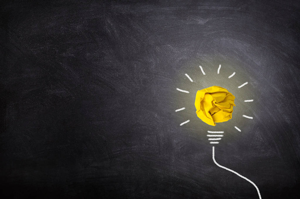 Concept d'idée d'affaires : l'éclairage jaune froissé d'ampoule de boule de papier se développent autour sur le tableau
. - Photo, image