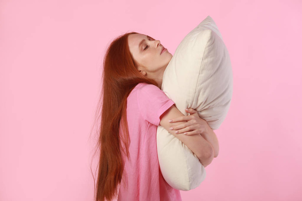 beautiful young woman with red hair sleeps on a pillow on a pink background - Zdjęcie, obraz