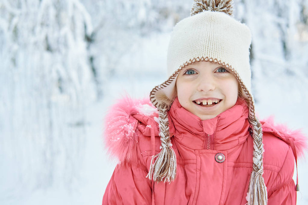 Closeup beautiful Caucasian little girl in winter on a walk in the park. Snowy beautiful winter - Foto, afbeelding