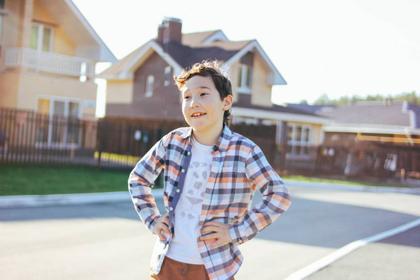 Portré mosolygós tinédzser fiú a napos utcában ház falu a háttérben - Fotó, kép