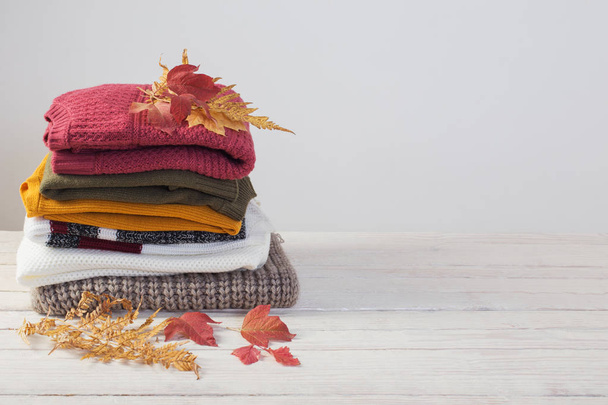 stack of sweaters with autumn leaves  on  white wooden table - Photo, Image