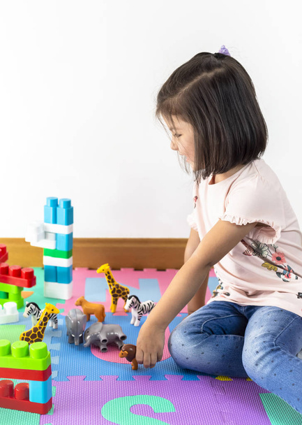 Petite fille jouant avec des jouets d'animaux à la maison ou jardin d'enfants
. - Photo, image