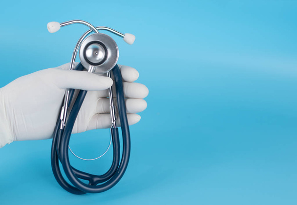 A doctor wearing sterile gloves is carrying a stethoscope for diagnostic purposes for patient illness. - Photo, Image