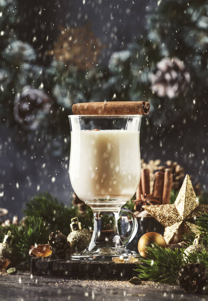 Christmas or New Year Eggnog alcoholic cocktail - hot winter drink with milk, eggs and rum, sprinkled with cinnamon and nutmeg in glass on gray background, copy space - Foto, immagini