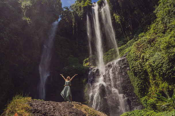 Woman in turquoise dress at the Sekumpul waterfalls in jungles on Bali island, Indonesia. Bali Travel Concept - Фото, зображення