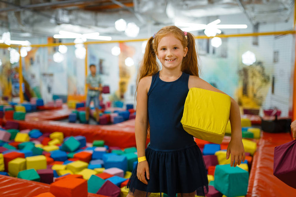 Adorable little girl playing with soft cube, playground in entertainment center. Play area indoors, playroom - Photo, Image