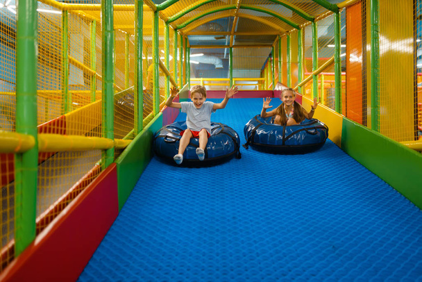 Kleines Mädchen reitet auf Tubing, Spielplatz im Unterhaltungszentrum. Spielbereich drinnen, Spielzimmer - Foto, Bild