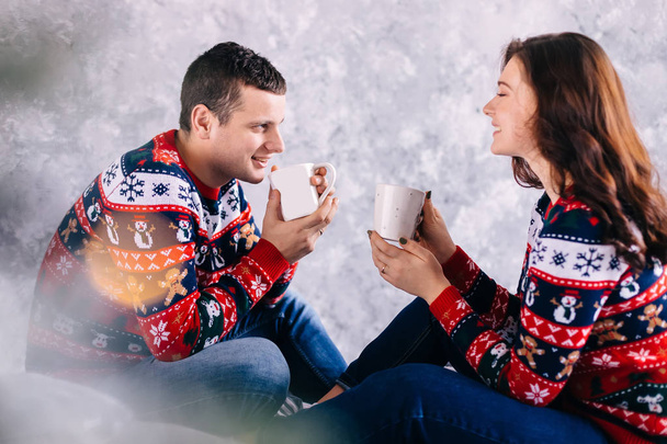 couple in love sitting and drinking hot drink on wall background - Фото, изображение