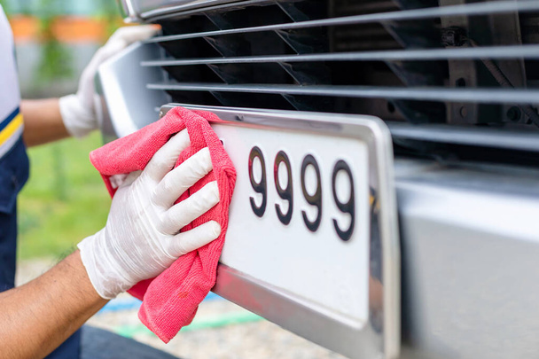 Man using red cloth to cleaning front car plate number - Foto, Bild
