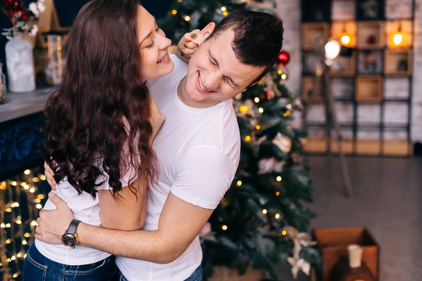ragazzo e ragazza in t-shirt bianche si divertono vicino all'albero di Natale  - Foto, immagini