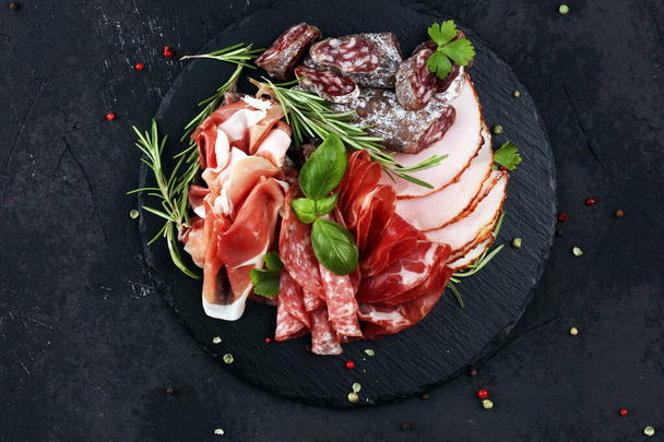 Placa de corte de mármore com presunto, bacon, salame e salsichas
 - Foto, Imagem