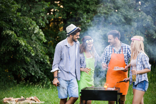 Friends making a barbecue together outdoors in the nature - Foto, Imagem