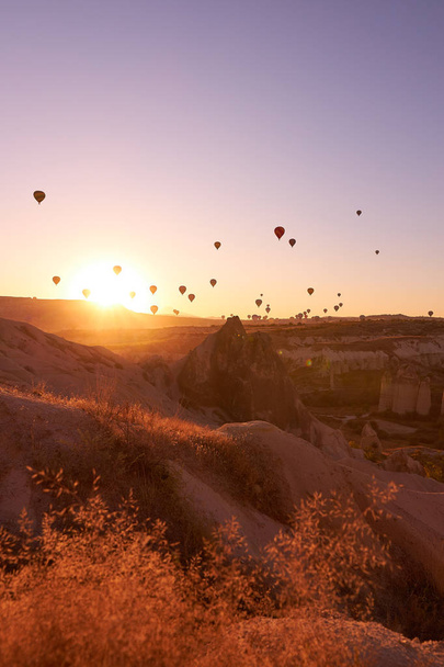 sunrise photo in Cappadocia with air balloons in the sky over sandy hills - Foto, Bild