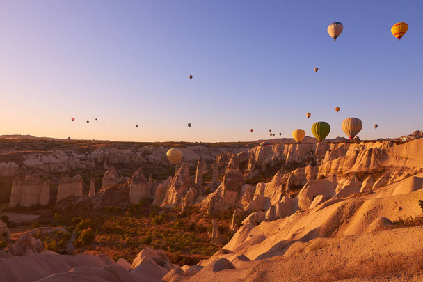 sunrise photo in Cappadocia with air balloons in the sky over sandy hills - Photo, Image