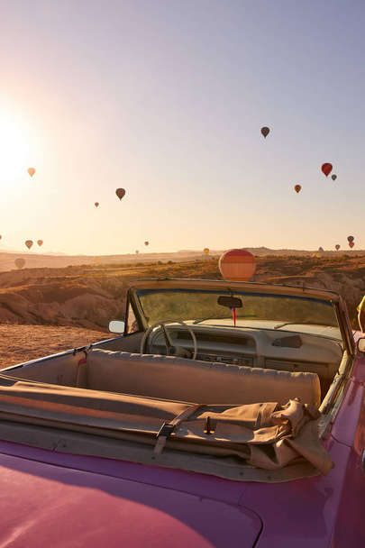 red retro cabriolet with leather inside on the background of blue sky with balloons over sand hills - Fotoğraf, Görsel