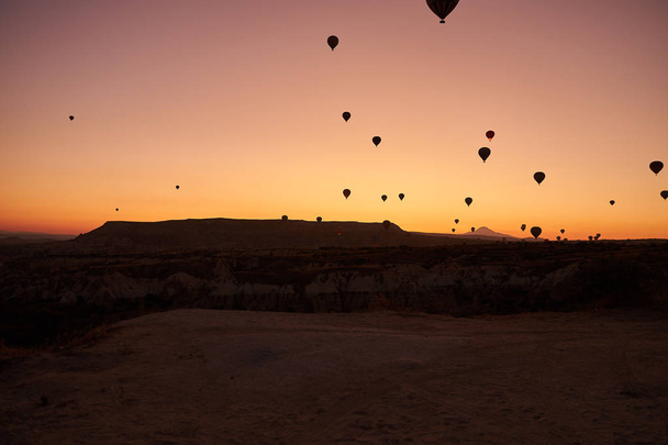 sunrise photo in Cappadocia with air balloons in the sky over sandy hills - Fotoğraf, Görsel