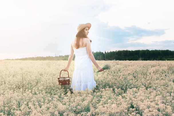 Κορίτσι με λευκό φόρεμα σε ένα χωράφι με κίτρινα λουλούδια που ανθίζουν - Φωτογραφία, εικόνα