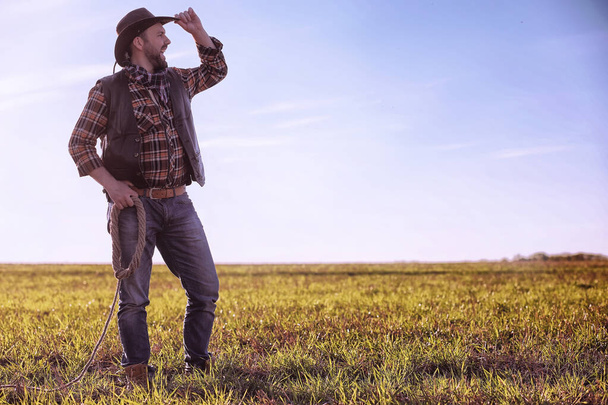 Cowboy standing in a field at sunset - Photo, image