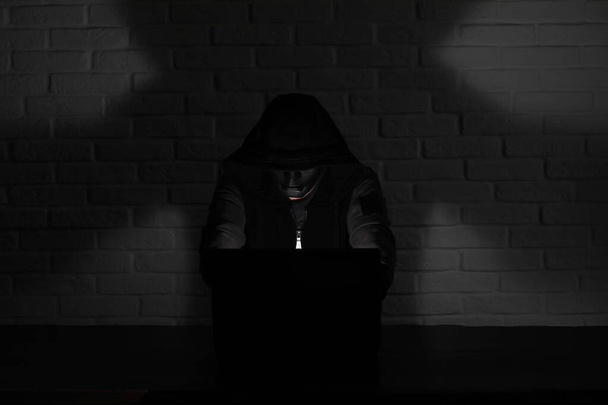 Hacker v černou masku a kapuce u stolu - Fotografie, Obrázek