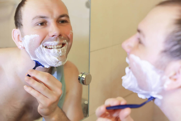 Un hombre se afeita en el baño por la mañana
 - Foto, imagen