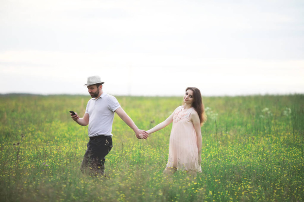Couple man and pregnant girl in the field - Foto, imagen