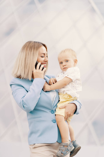 Portrait of a successful business woman in blue suit with baby - Photo, Image