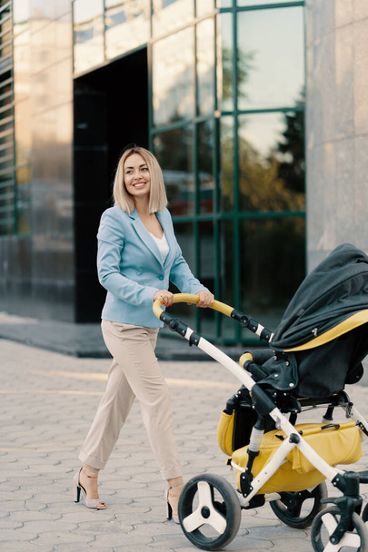 Portret van een succesvolle zakenvrouw in blauw pak met baby - Foto, afbeelding