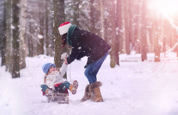 Um conto de fadas de inverno, uma jovem mãe e sua filha montam um trenó
 - Foto, Imagem