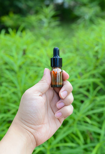 Botella de vidrio CBD Oil con fondo de marihuana, líquido de cannabis
 - Foto, Imagen