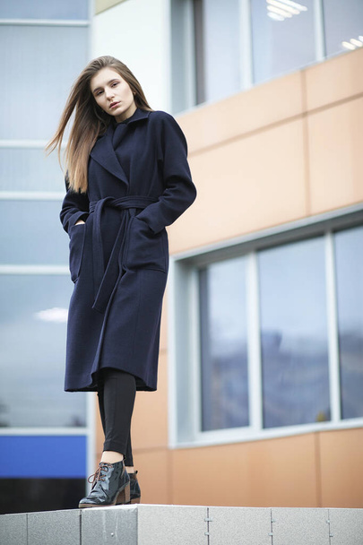 Όμορφο κορίτσι σε ένα παλτό στο επιχειρηματικό κέντρο της πόλης  - Φωτογραφία, εικόνα