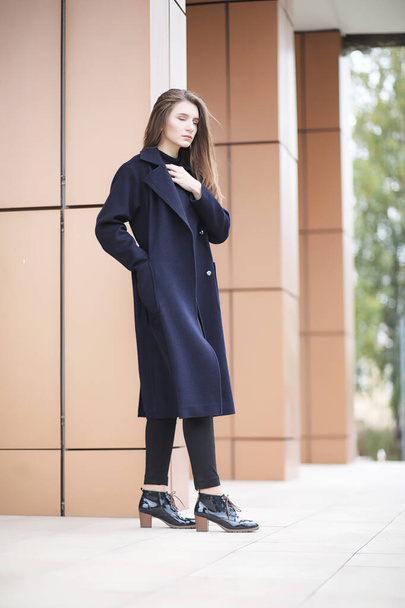 Beautiful girl in a coat in business downtown  - 写真・画像