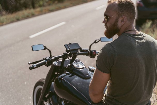 Back view of a bearded biker sitting on his motorcycle - Фото, зображення