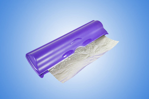Rollo de papel de aluminio en contenedor de plástico sobre fondo blanco a azul degradado, primer plano
. - Foto, Imagen