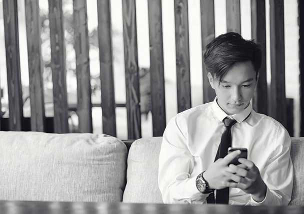 Ένας νεαρός επιχειρηματίας Ασίας είναι σε αναμονή για έναν εταίρο σε μια καφετέρια. BU - Φωτογραφία, εικόνα