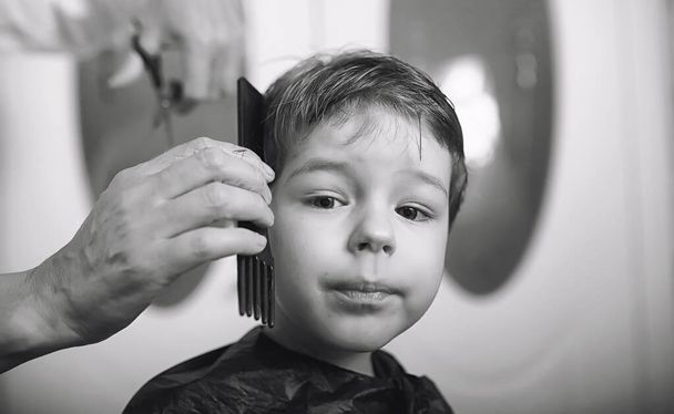 Hairdresser and boy. The boy is doing his hair. Cut hair child i - Foto, afbeelding
