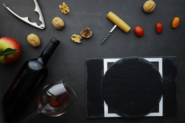 Бокал вина и бутылка черного вина. Орехи сыр и помидоры для S
 - Фото, изображение