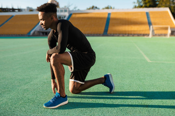 Boční pohled na mladé silné afroamerické sportovce na cvičení na stadionu - Fotografie, Obrázek