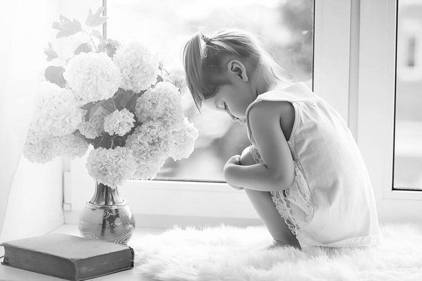 A little girl is sitting on the windowsill. A bouquet of flowers - Zdjęcie, obraz