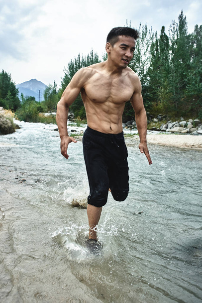 Asian athlete on a morning run on the river, Kazakh jogger in nature close-up  - Fotó, kép