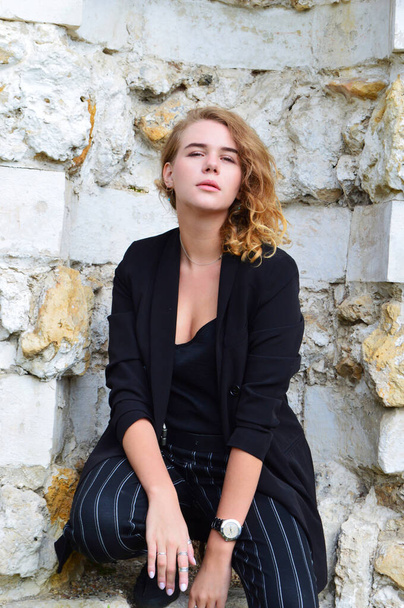 A sexy young woman in a business black suit is sitting - Photo, Image