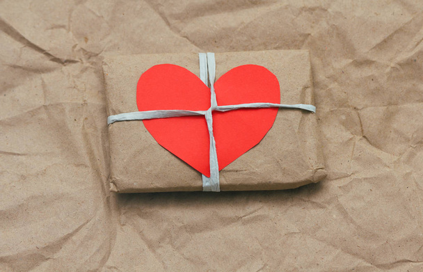 Soft pouch wrapped in craft paper and tie cord. Big red carton heart post card. Crumpled paper background texture. Delivery service. Online shopping. - Foto, Imagem