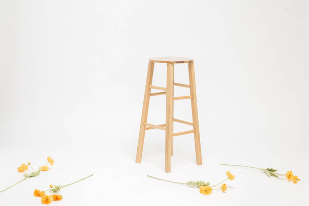 Packshot of a wooden stool and yellow flowers scattered on the floor on a white background - Fotografie, Obrázek