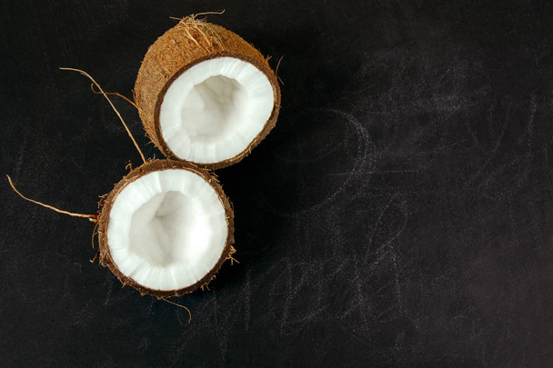 top view coconut halves on a black chalk board with copy space - Foto, imagen