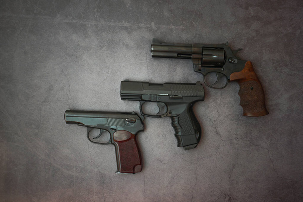 Πυροβόλα όπλα απλωμένα κατά μήκος της γραμμής. Τρία όπλα κοντά σε ένα γκρι τσιμεντένιο φόντο. αντίγραφο χώρου - Φωτογραφία, εικόνα